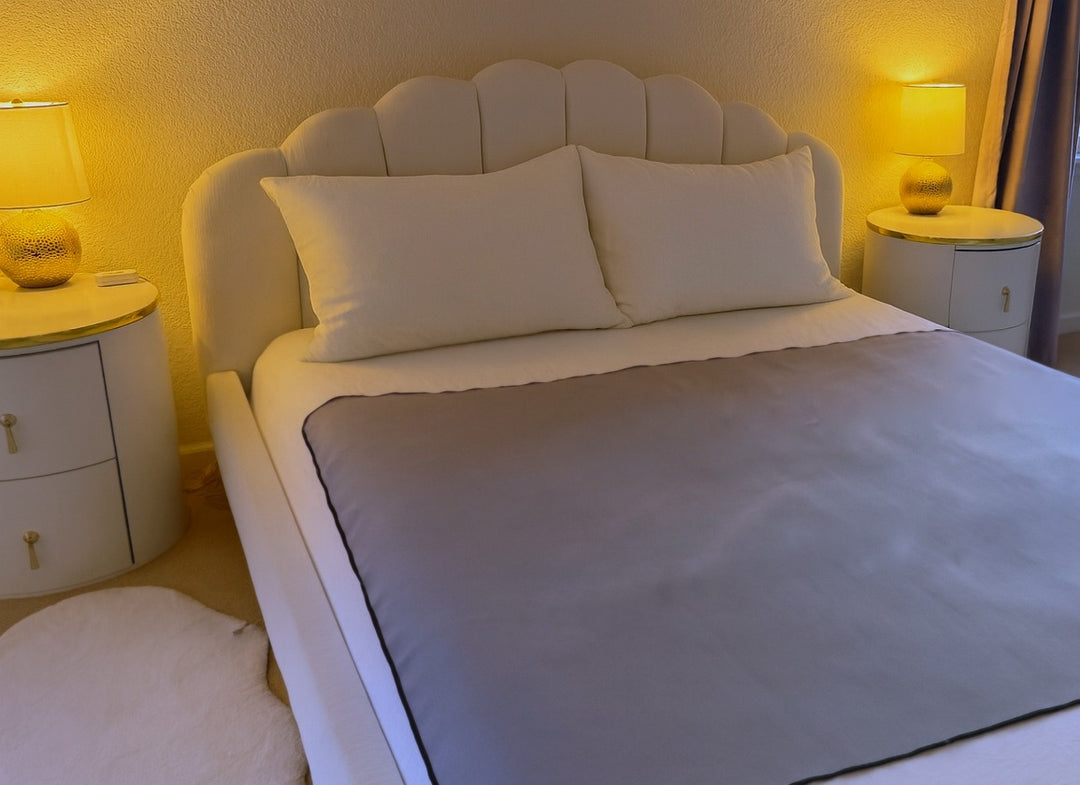 Moonstone organic cotton Venus Mat on bed in styled bedroom — soft grey waterproof sex mat lies flat, stays put, PFAS-free and made in the USA